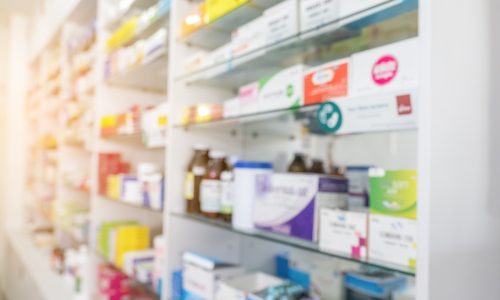 Blurry view of drug store and pharmacist. Blurred clean pharmacy with medicine on shelves. Defocus white drugstore Blurry view of drug store and pharmacist. Blurred clean pharmacy with medicine on shelves. Defocus white drugstore